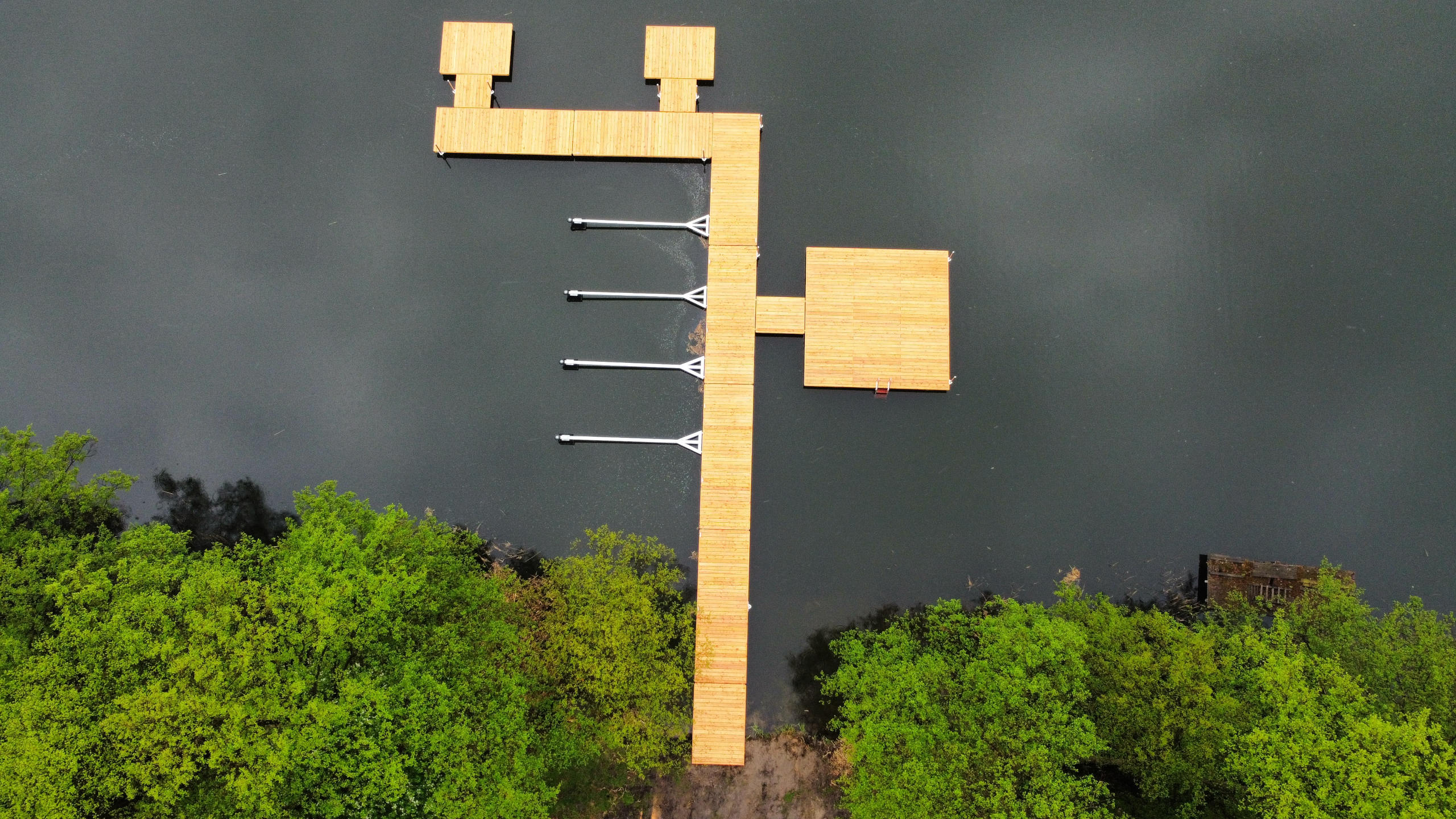 Widok z góry dużego rozbudowanego pomostu z odczepianą tratwą i miejscem do cumowania łodzi